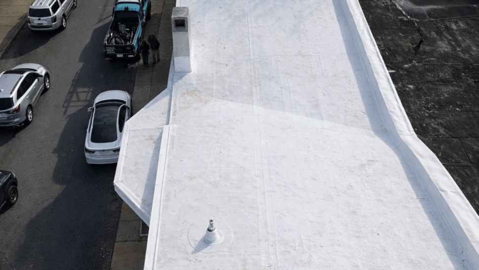 Top-down view of a flat roof next to a street with parked cars
