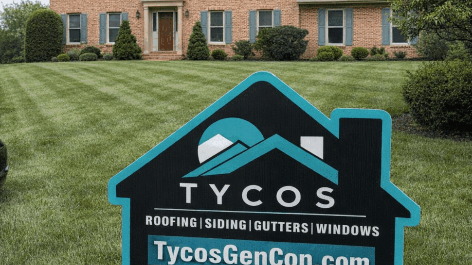 Tycos yard sign on the front lawn of a two-story brick house.