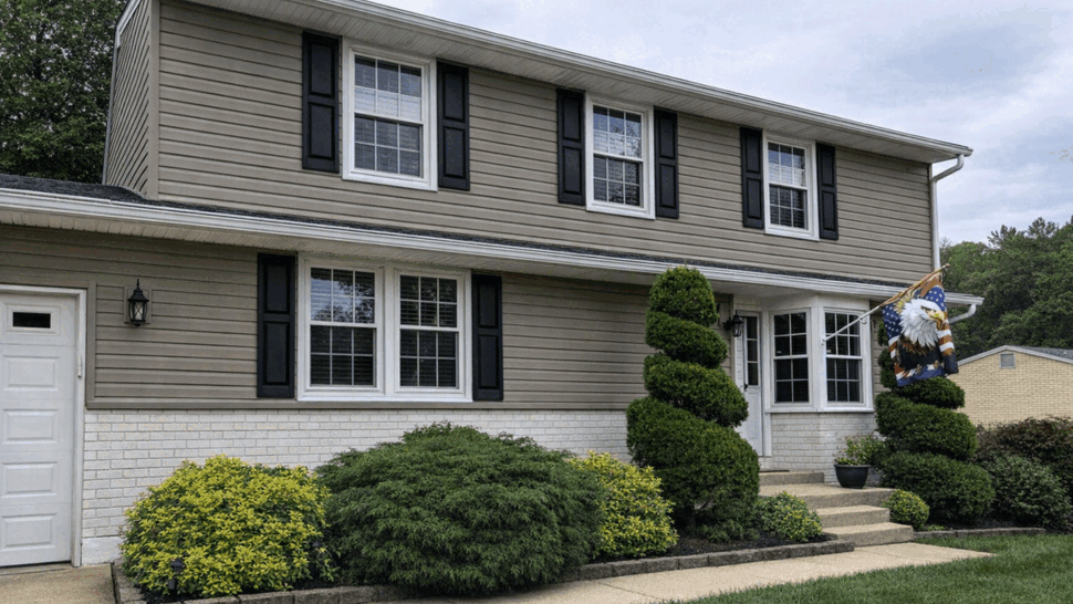 Two-story beige house with white brick and black shutters.
