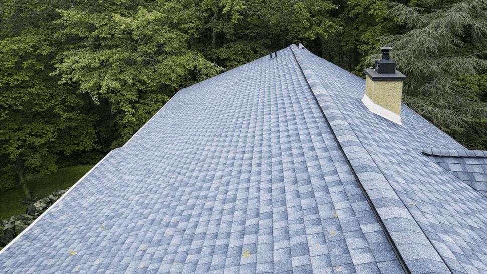 Aerial rooftop ridge view on blue shingles | Tycos Roofing And Siding Inc Aerial rooftop view showing blue shingle ridge and surrounding trees.