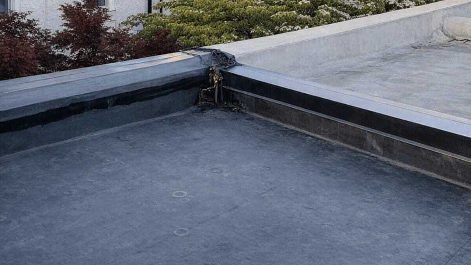 Flat rubber roof corner with parapet and neighboring buildings