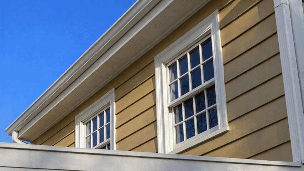 Upper double-hung windows with beige siding and white soffit and gutter above.