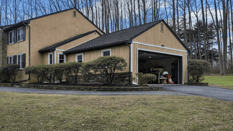Two-story home with attached garage, asphalt roof and front shrubs.