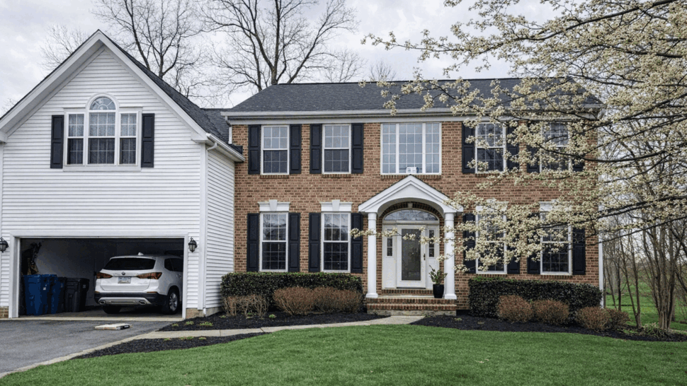 Two-story brick and siding house with dark shingle roof and front lawn