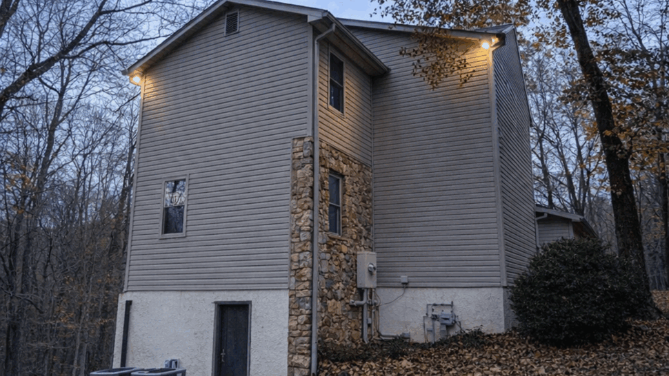 Side view of house with stone chimney, siding, and HVAC units