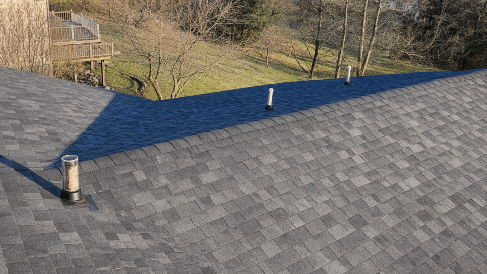 Close-up of an asphalt shingle roof valley with multiple vent pipes.