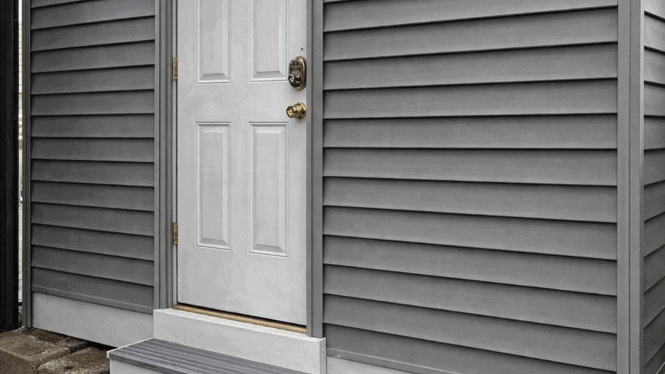 Entry Door with Vinyl Siding | Tycos Roofing And Siding Inc White exterior door with three steps and fresh gray vinyl siding