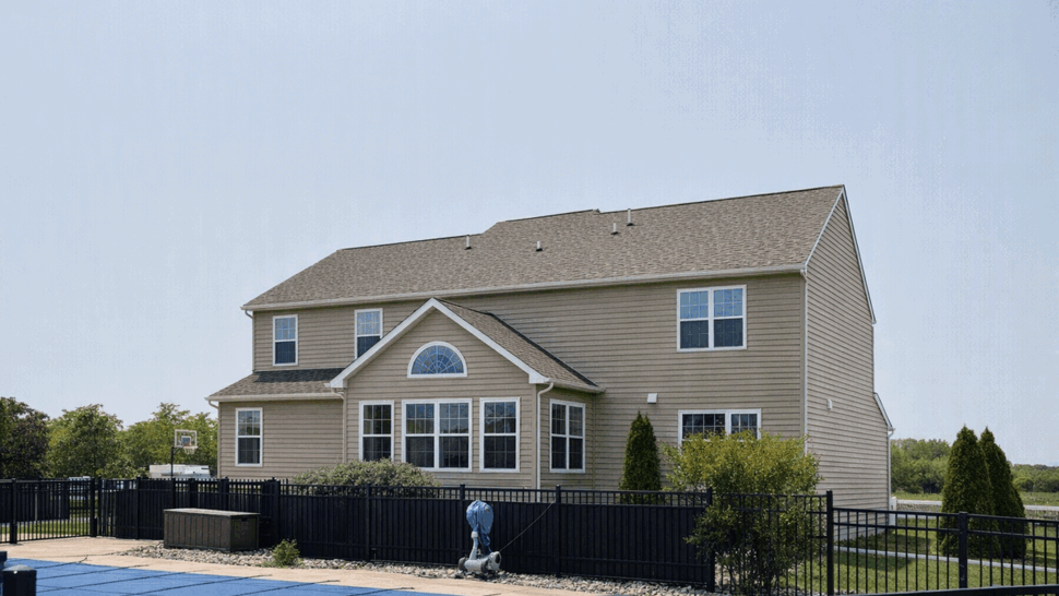 Rear of home with fenced pool, large windows, and landscaped backyard.