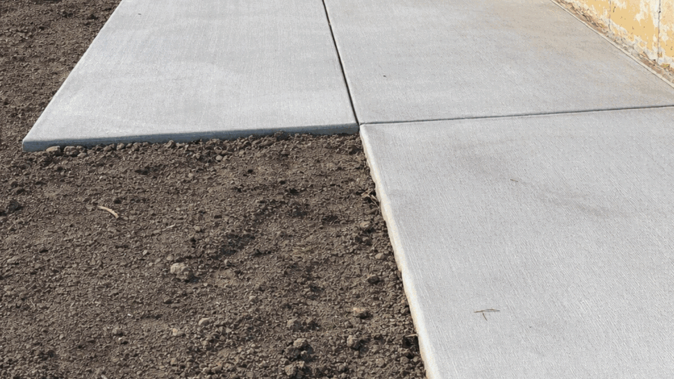 Fresh concrete patio slabs next to brick foundation ready for outdoor use