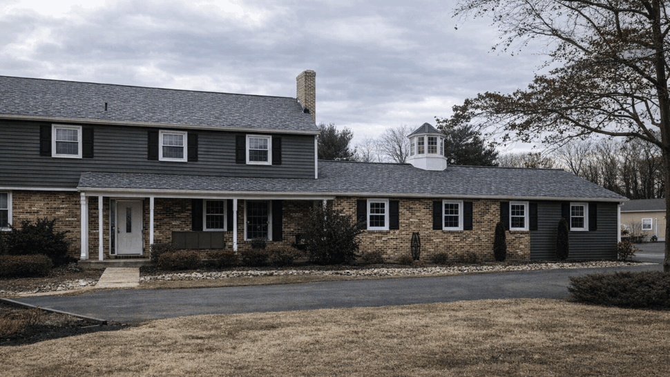 Front view of brick and siding house with asphalt shingle roof and cupola.