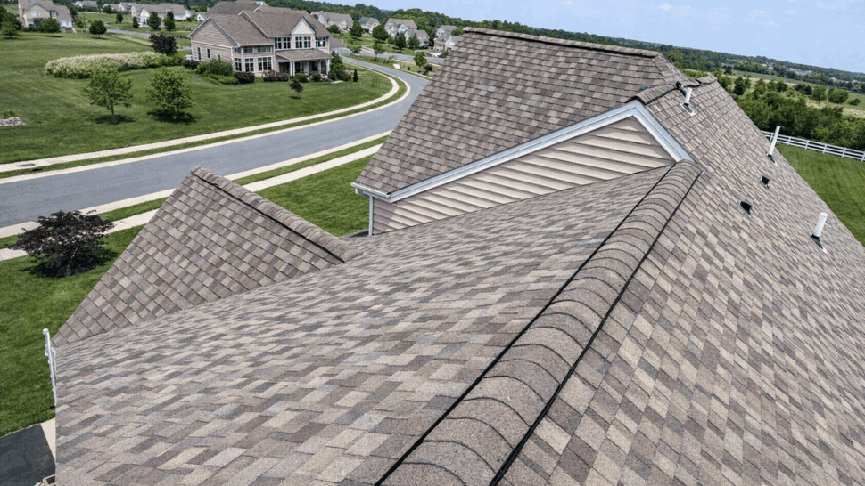 Aerial view along roofline showing shingle patterns and surrounding neighborhood.