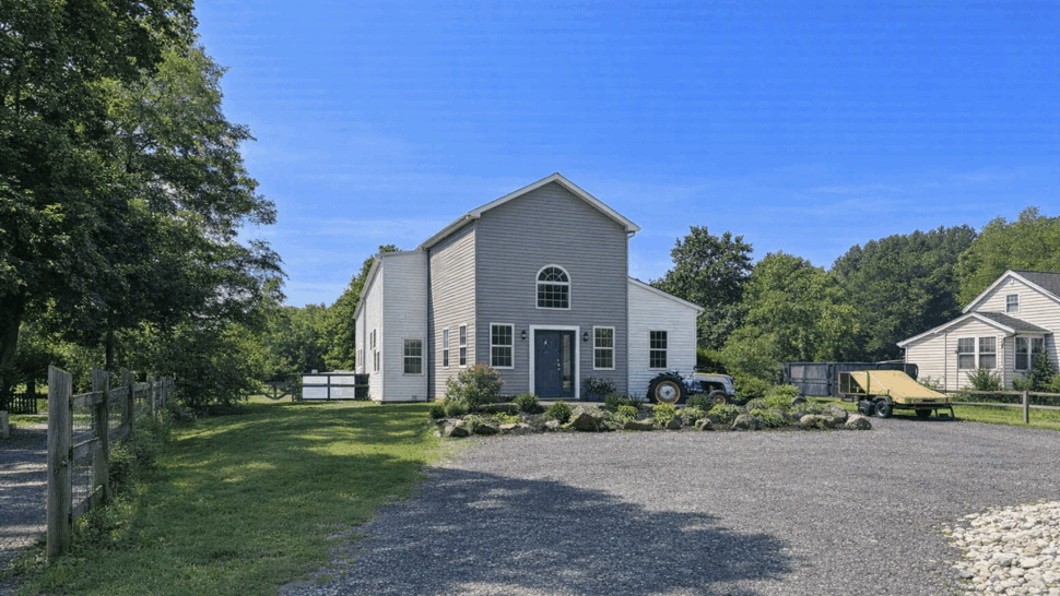 Two-story front entry with double doors | Tycos Roofing And Siding Inc Front view of a two-story house with central double doors and landscaped gravel driveway
