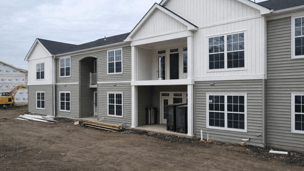Two-story multi-unit building with gray vinyl siding under construction