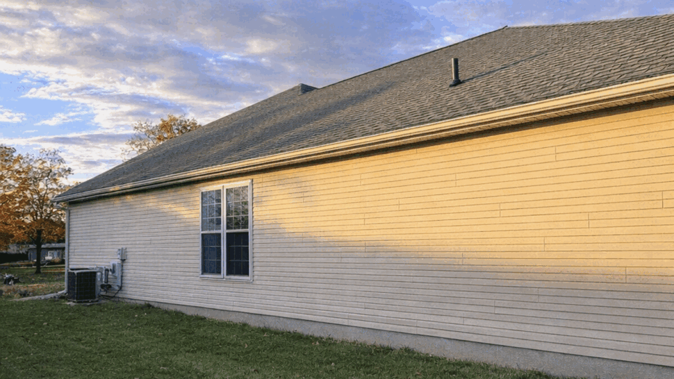 Side exterior with gutters installed | Tycos Roofing And Siding Inc Side view of a house showing white siding and gutters at sunset.