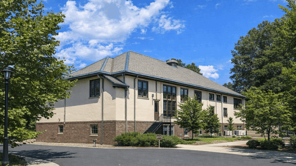 Side perspective showing stucco siding, brick base and roofline with windows