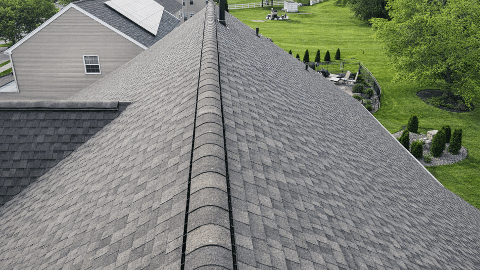 Long centered ridge view of asphalt shingle roof overlooking backyard and neighboring homes
