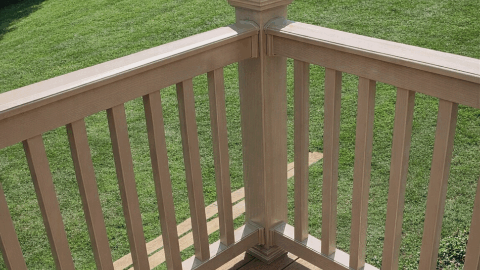 Brown deck overlooking a green backyard with white corner railing
