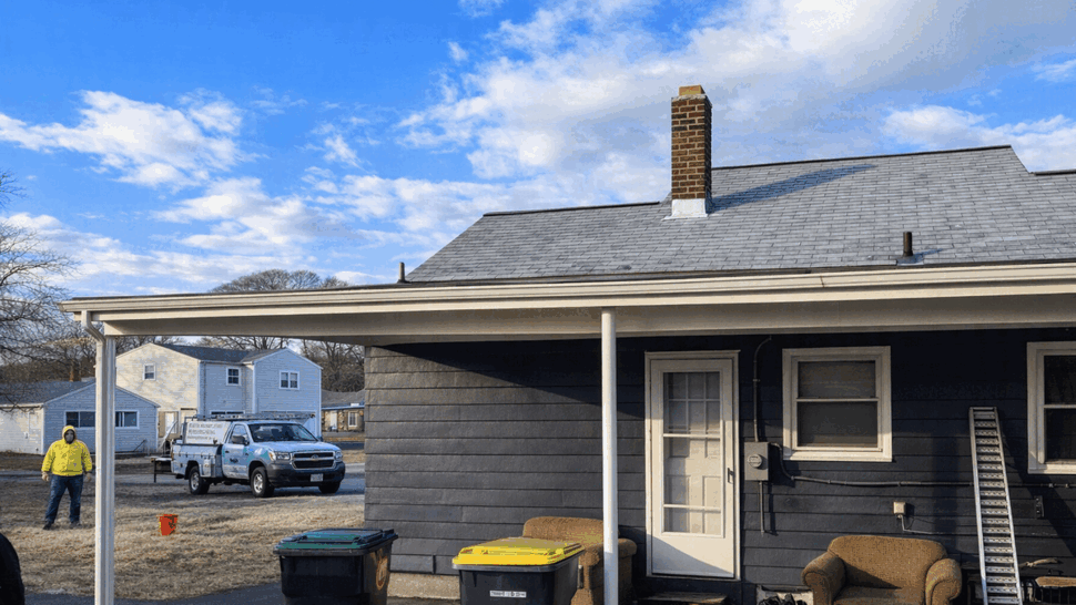 Covered Porch Roof and Gutters | Tycos Roofing And Siding Inc Covered porch beside a blue-sided home with gray shingles and gutters.