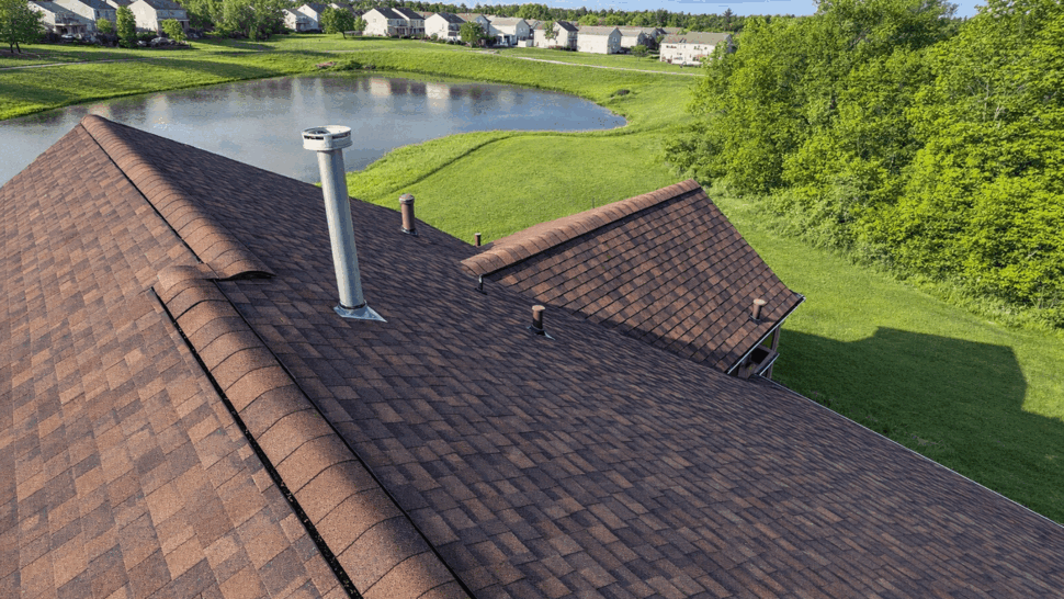Aerial Roof Over Pond View | Tycos Roofing And Siding Inc Aerial roof view with chimney, ridge vent and pond in the distance