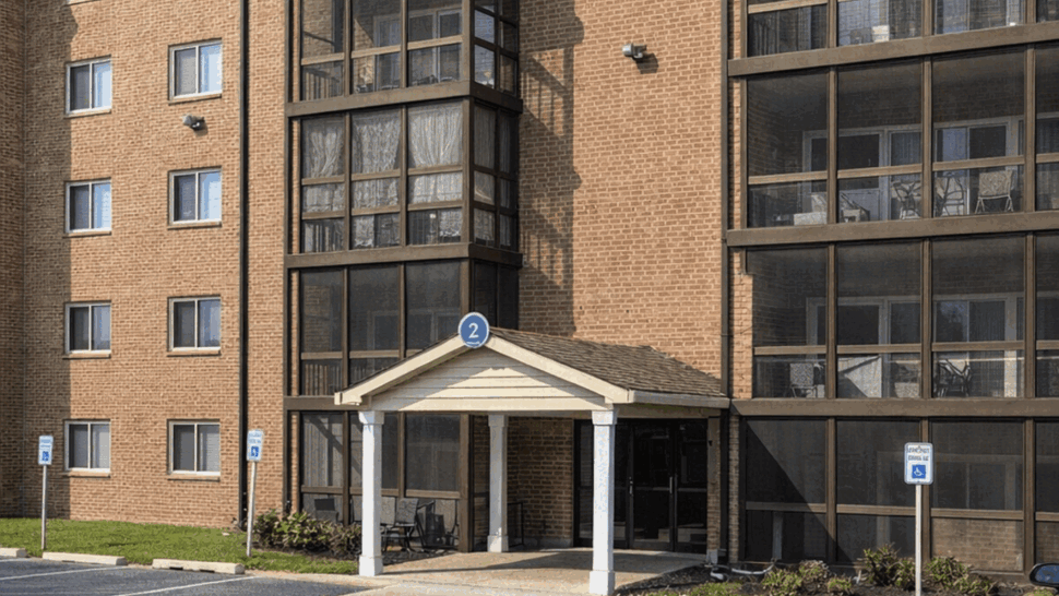 Brick apartment building with screened balconies and covered entrance.