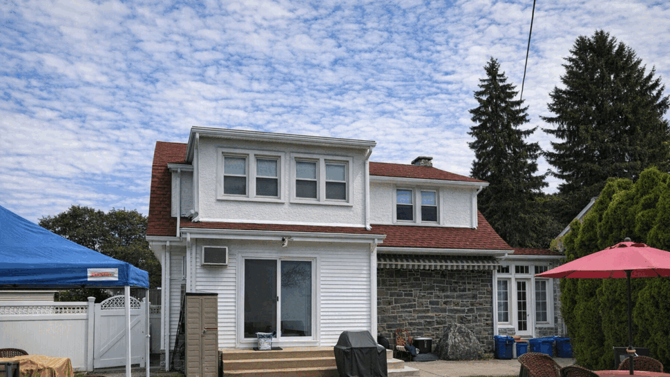 Backyard view with white siding, sliding patio door, and red roof