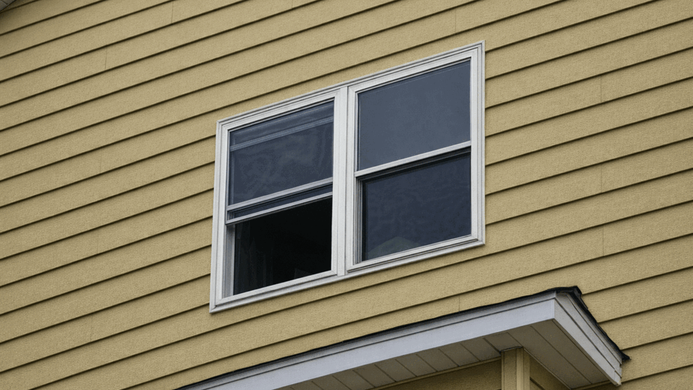 Upper double-hung window set in yellow horizontal siding