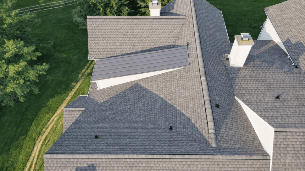 Overhead view of shingled roof featuring a raised metal panel accent and chimneys.