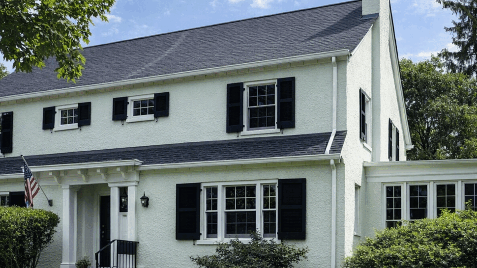 Front view of a colonial house with dark asphalt shingle roof and white siding.