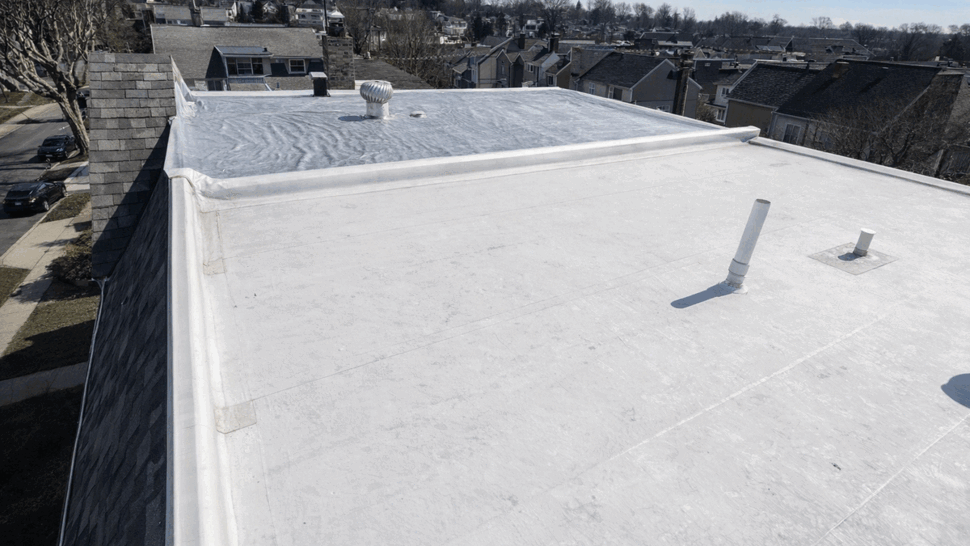 Aerial view of a white flat roof membrane with vents and perimeter flashing.