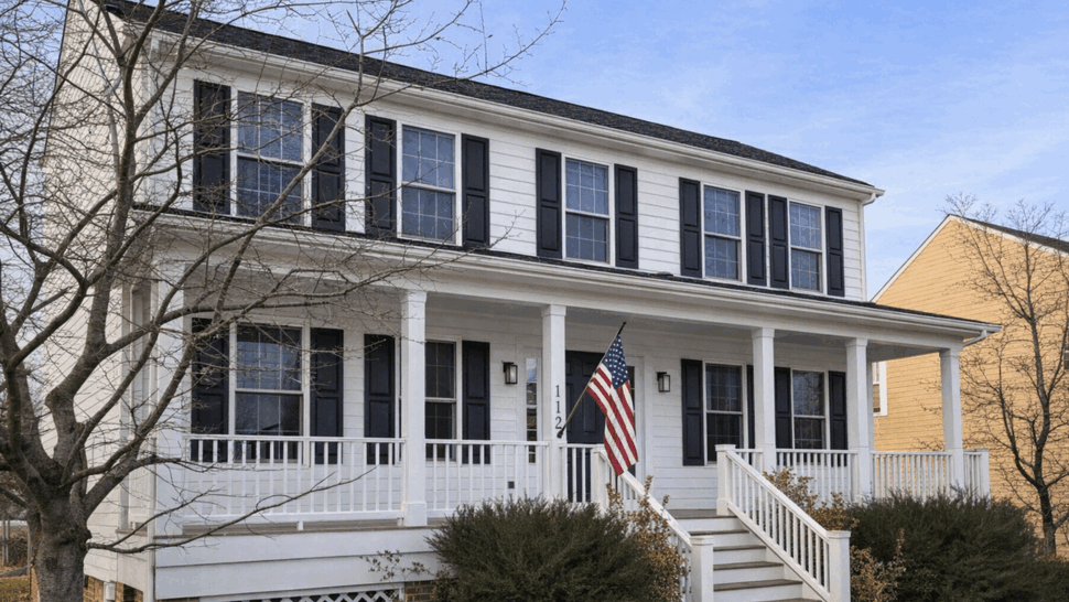 Two-story white house with front porch, black shutters and an American flag