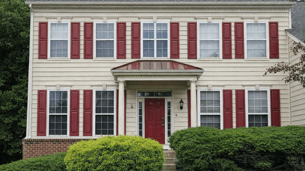 Close-up of two-story front facade with red shutters and covered entry