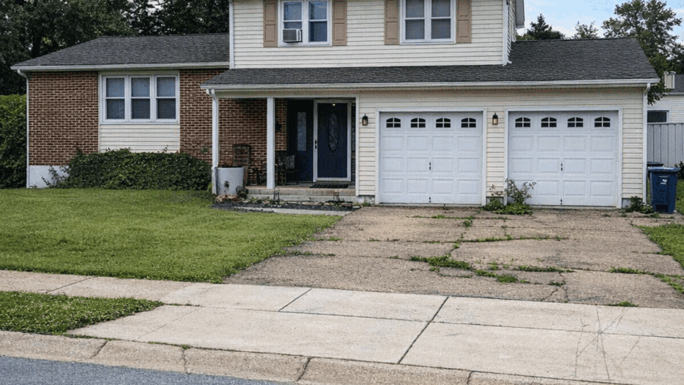 Two-story home with updated siding | Tycos Roofing And Siding Inc Two-story suburban house with beige siding, brick and attached double garage.