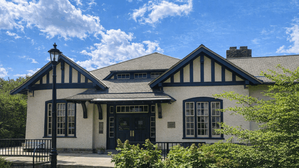 Front facade of a Tudor-style building with gabled roof and entrance under blue sky