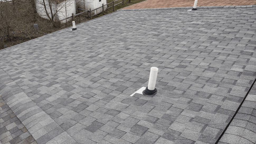 Roof plumbing vent on shingles | Tycos Roofing And Siding Inc Close-up of roof shingles with white plumbing vent boots