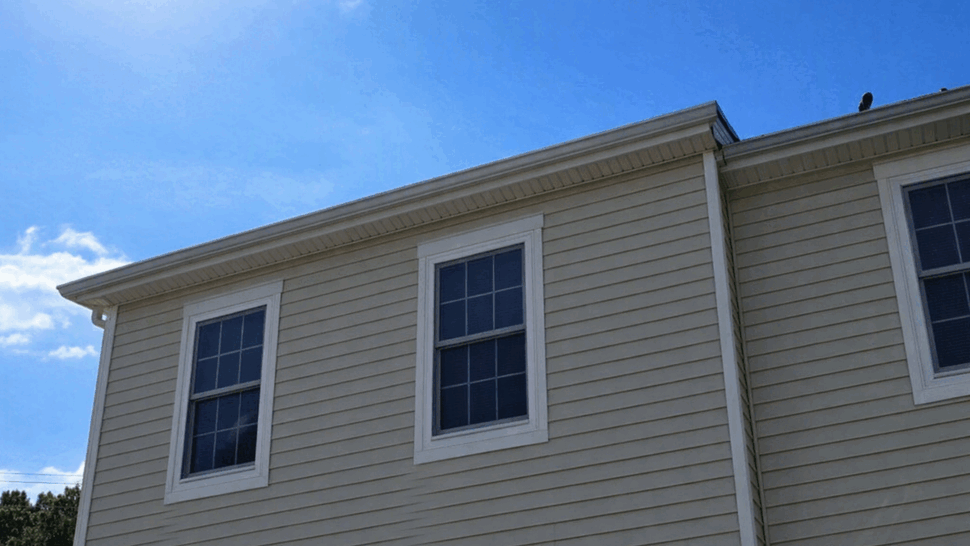 Beige House Siding and Windows | Tycos Roofing And Siding Inc Side view of a house showing beige siding, two windows and a gutter