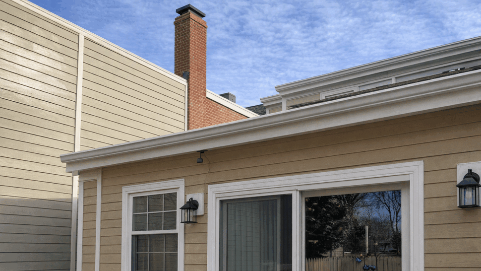Beige siding with white trim and sliding glass door under a gutter.