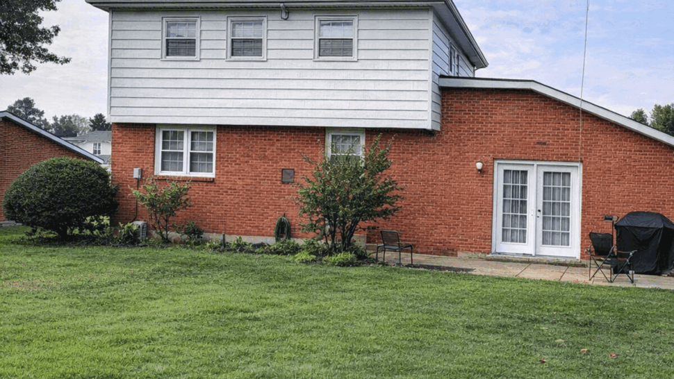 Two-story brick and white siding house with dark shingle roof and green lawn