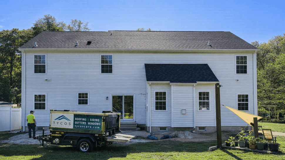 Rear of house with Tycos trailer and crew preparing materials for roofing work