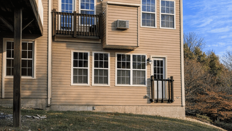 Rear Vinyl Siding and Windows | Tycos Roofing And Siding Inc Rear elevation of a townhouse with tan vinyl siding and multiple windows.
