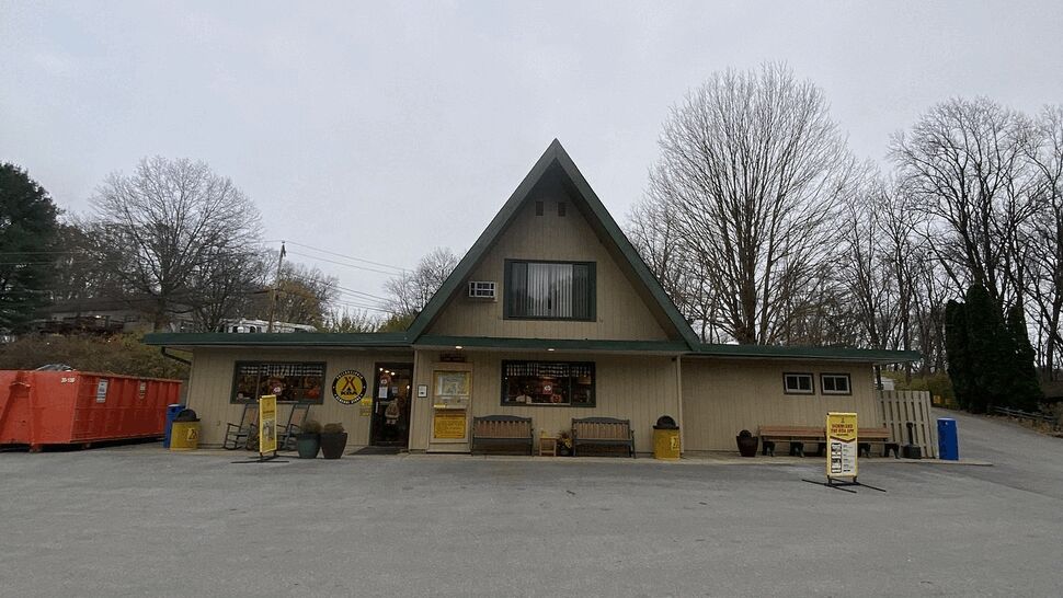 A-frame commercial building with beige siding and a large empty parking area.