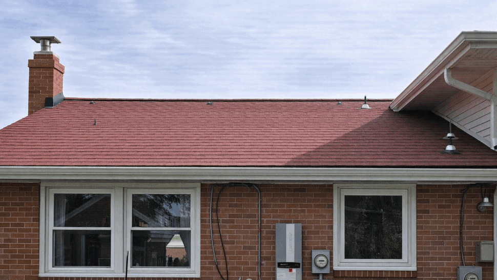 Rear roof slope with chimney, red shingles and roof fixtures.