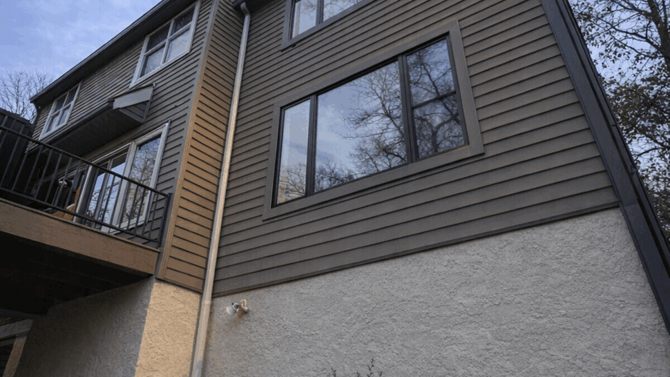 Angled view of siding with visible downspout and deck rail