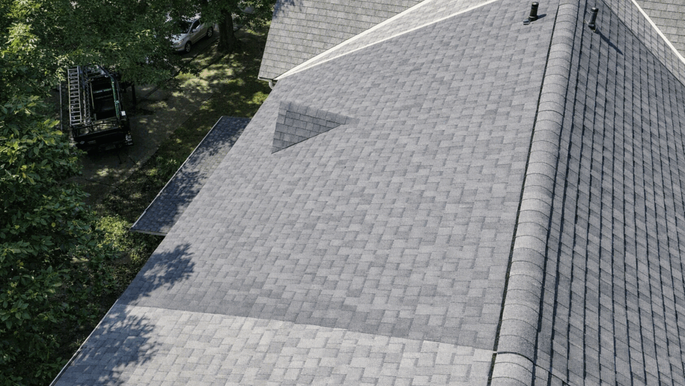 Drone roof ridge and vents | Tycos Roofing And Siding Inc Drone view of a grey roof ridge with vents and tree shadows.