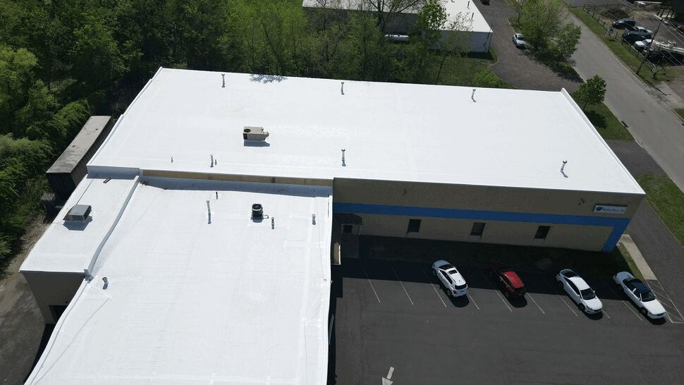 Aerial view of a white commercial flat roof and adjacent parking lot