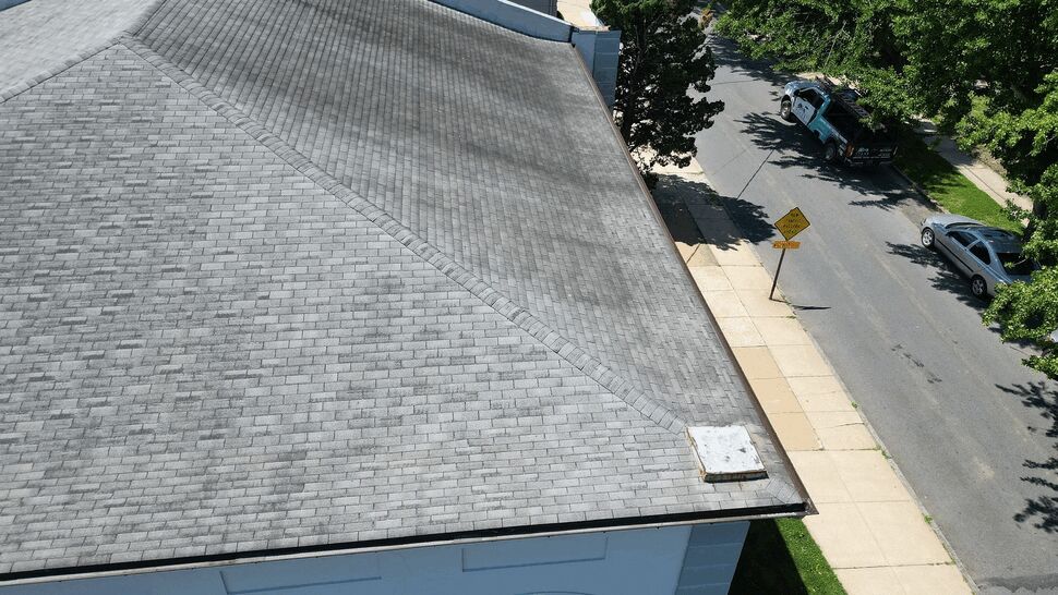 Aerial view of a gray shingle hip roof above a residential street.