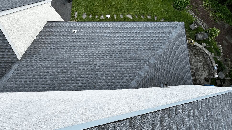 Aerial view of a newly installed gray shingle roof over a residential yard
