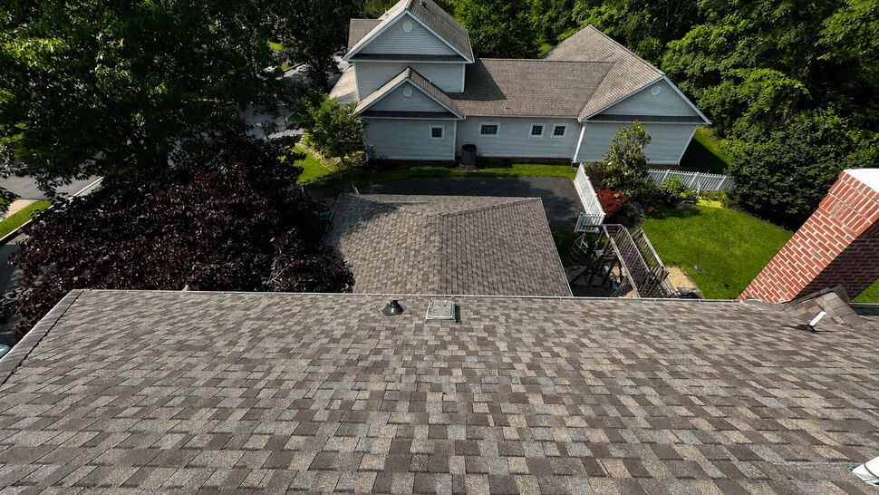 Aerial view of a residential shingled roof looking down toward the backyard and garage.