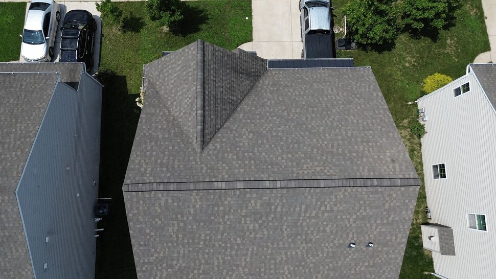 Top-down drone view of asphalt shingle roof between homes