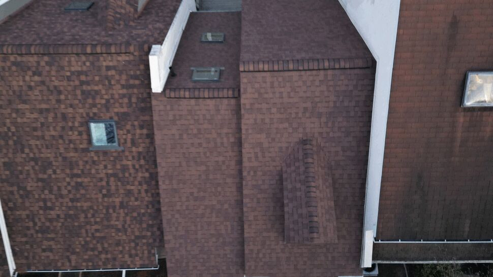Aerial drone view of brown shingled roofs with skylights and adjoining structures