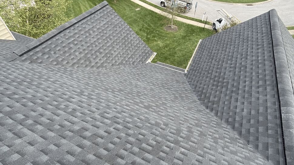 Top-down view of gray asphalt shingles on a residential roof looking over the street.